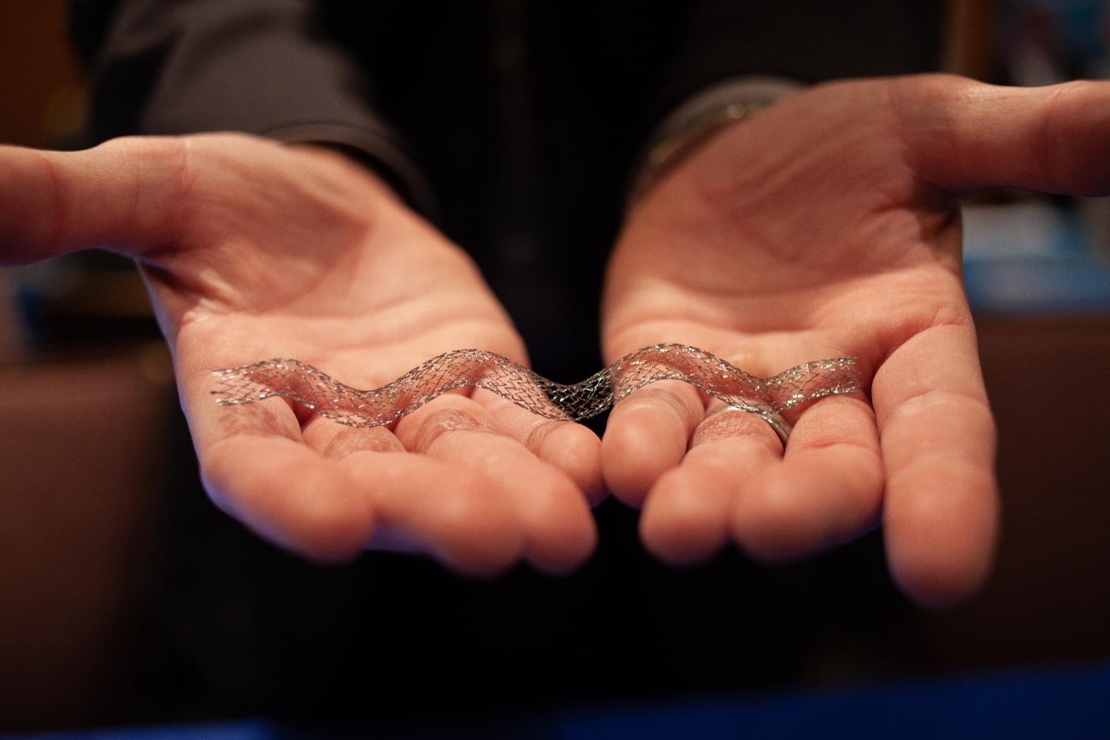 Two doctors hands hold out a stent used for vascular surgery.