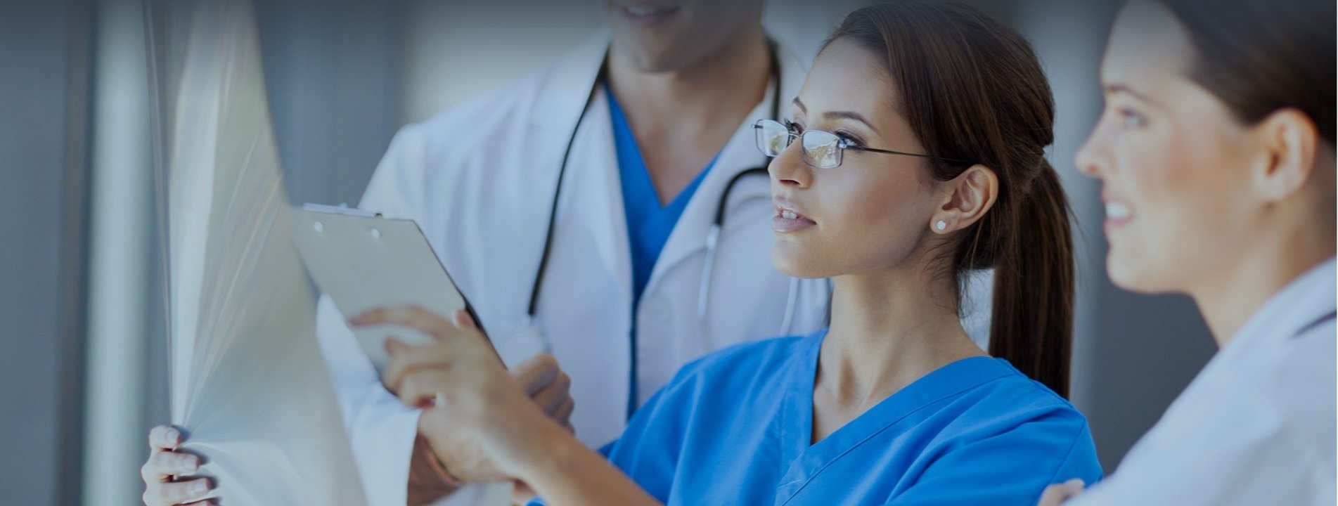 Female surgeon with a clipboard looks over a chart with her surgical colleagues.
